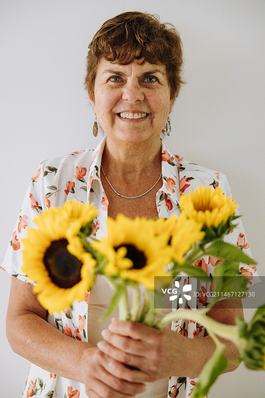 手持向日葵的微笑老年妇女肖像，澳大利亚新南威尔士州悉尼图片素材