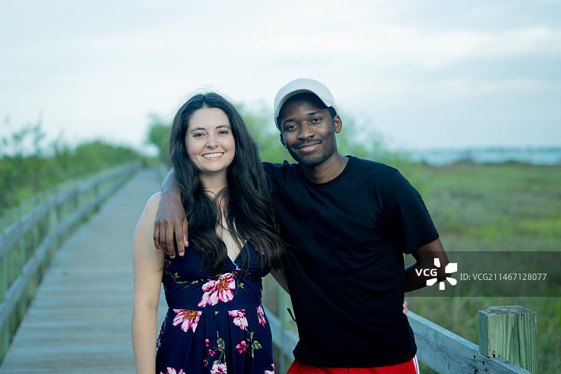 一对面带微笑的夫妇站在木板路上，背景是天空，美国图片素材