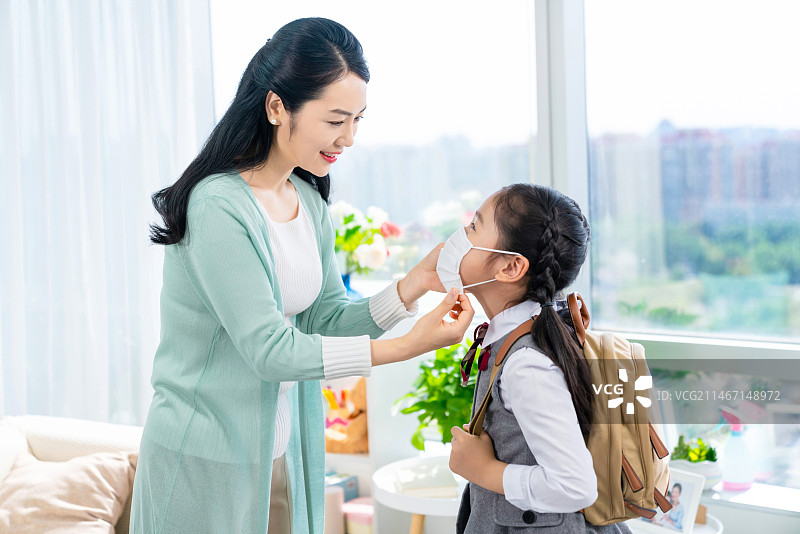 妈妈给女儿戴口罩图片素材