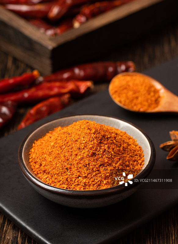 暗色木板上一小碟辣椒粉图片素材