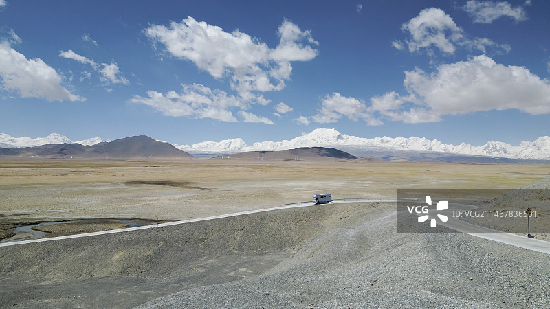 喜马拉雅山脉下，雪山群与旷野里的一辆房车图片素材