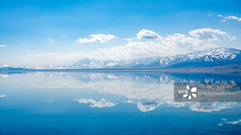 赛里木湖蓝天白云下的雪山和湖泊倒影图片素材