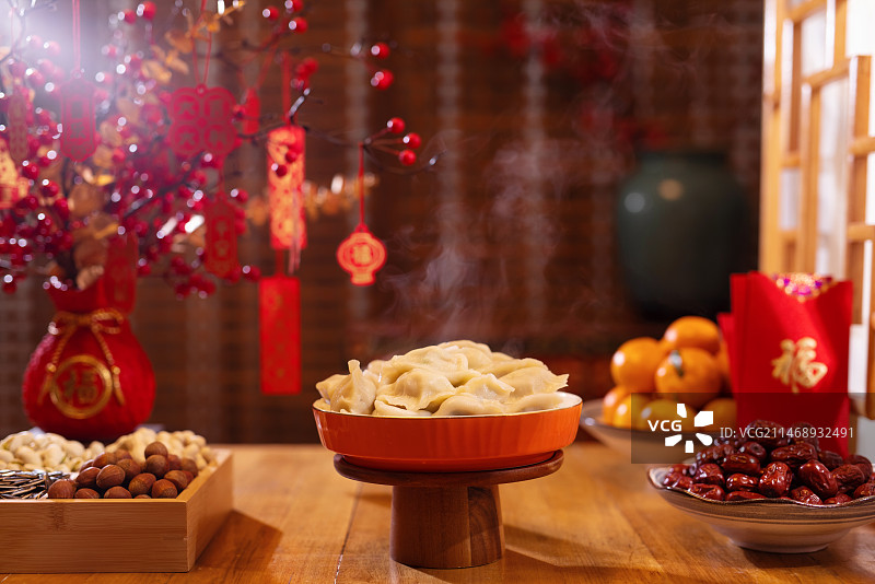 一盘热气腾腾的饺子摆放在喜庆的环境中,新年,春节,中国年图片素材