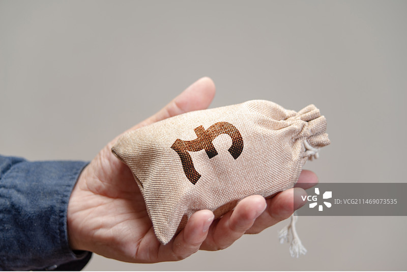 手里拿着印有英镑符号的钱袋子特写照片图片素材