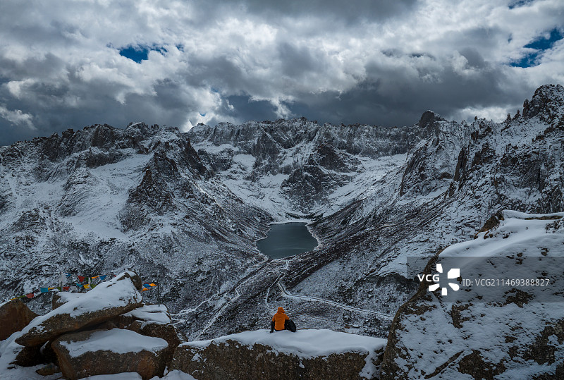 航拍男人坐在莲宝叶则的山顶悬崖边图片素材