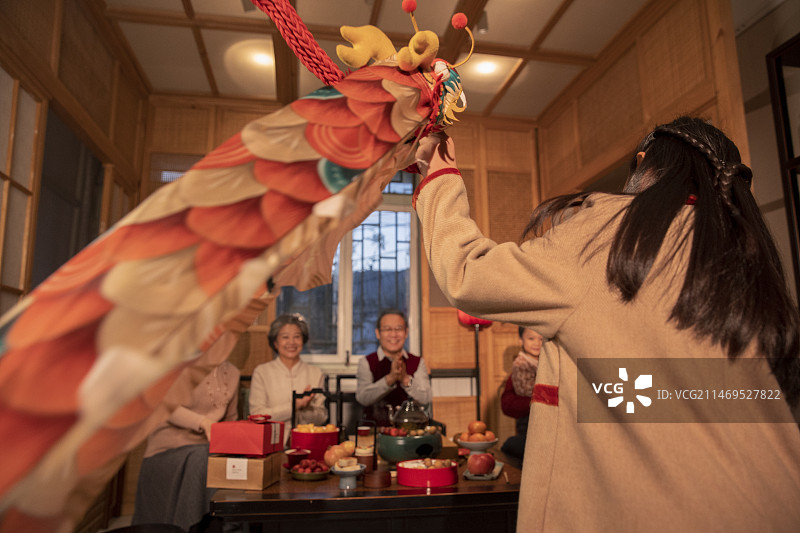 东方家庭过年：幸福一家人在客厅围炉煮茶、小女孩给家人表演舞龙图片素材