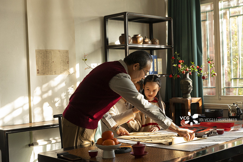 东方家庭过年：老年夫妇在书房教孙女写毛笔字图片素材