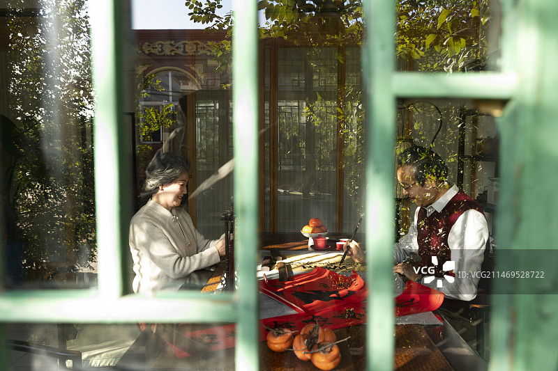 东方家庭过年：老年妻子在书房给正在写毛笔字的丈夫拍照、录视频图片素材