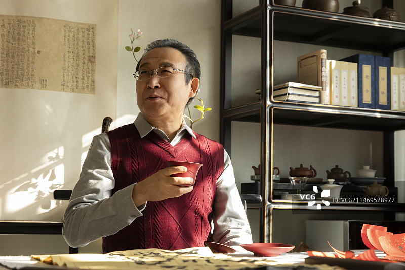 东方家庭过年：老年男人在书房喝茶、写春联图片素材