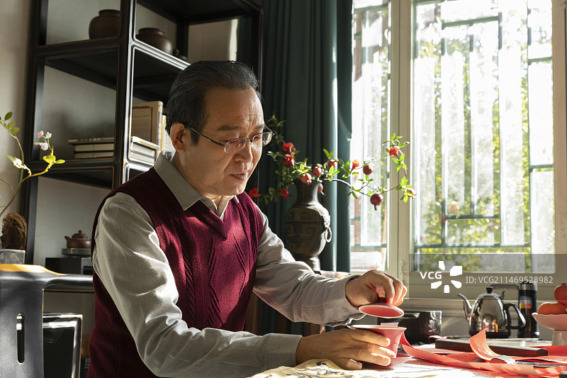 东方家庭过年：老年男人在书房喝茶、写春联图片素材