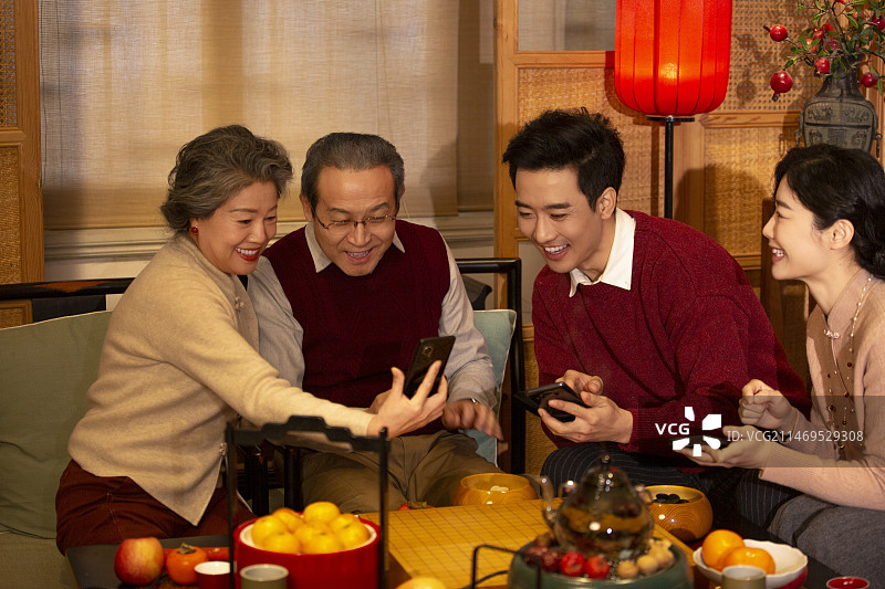 东方家庭过年：一家人在客厅用手机抢红包图片素材