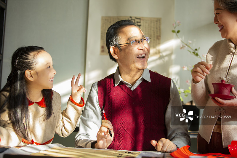 东方家庭过年：老年夫妇和孙女在书房写毛笔字、喝茶、聊天嬉戏图片素材