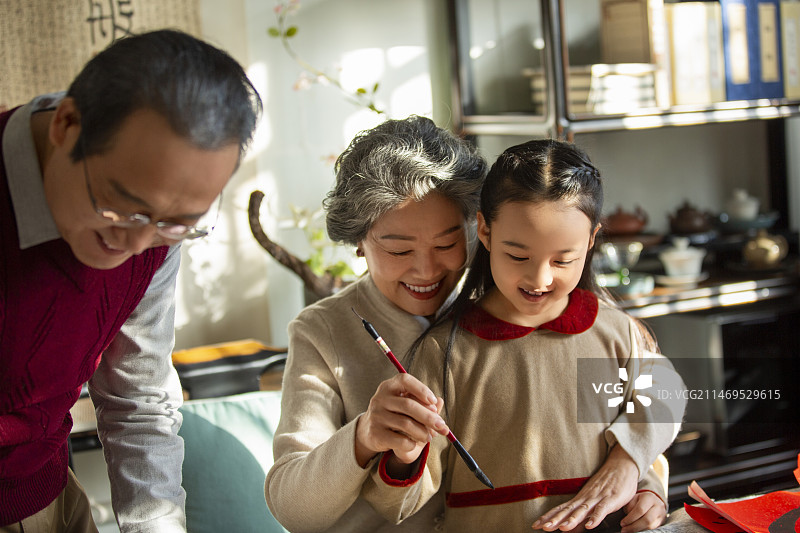 东方家庭过年：老年夫妇在书房教孙女写毛笔字图片素材