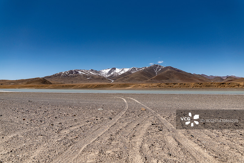 雪山下的雅鲁藏布江边的车辙印车轮痕迹图片素材