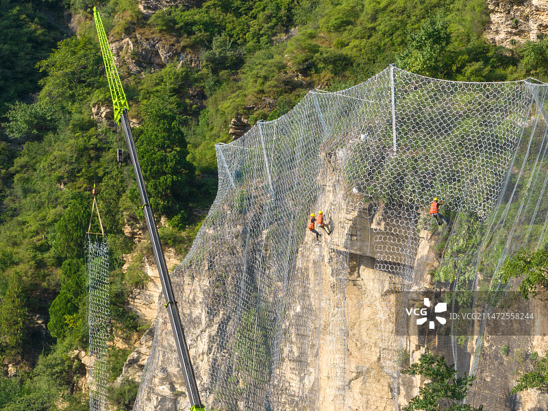 航拍工人公路边进行山体边坡防护网施工图片素材