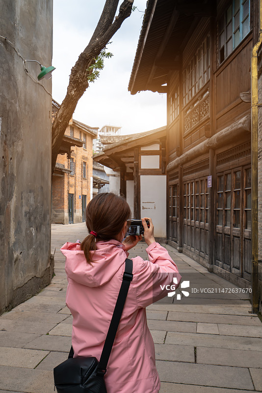 一个亚洲女性在古城街道拍照的背影图片素材