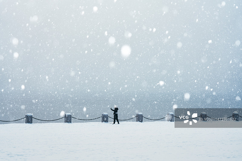 一位年轻的女士在大雪中用手机拍照图片素材