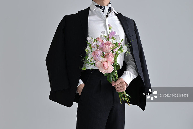 灰色背景下拿着花束的西装男人图片素材
