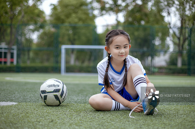 坐在足球上系鞋带的小女孩图片素材