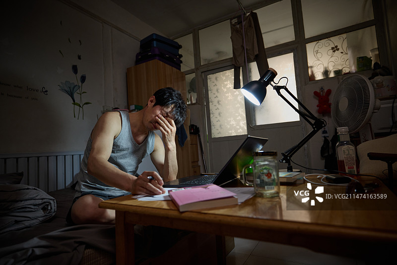 夜晚中年男人在出租房内使用笔记本电脑图片素材