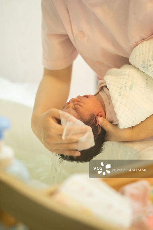 月子中心的护士给刚出生5天的宝宝洗头洗澡图片素材