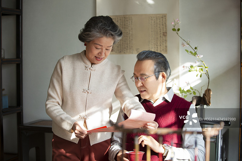 东方家庭过年：老年夫妇在书房看春联、喝茶、聊天图片素材