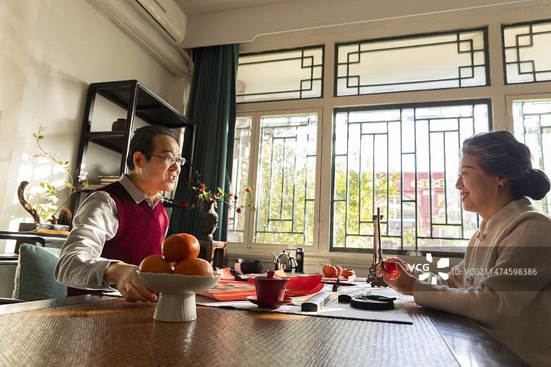 东方家庭过年：老年夫妇在书房喝茶聊天、写春联和福字图片素材