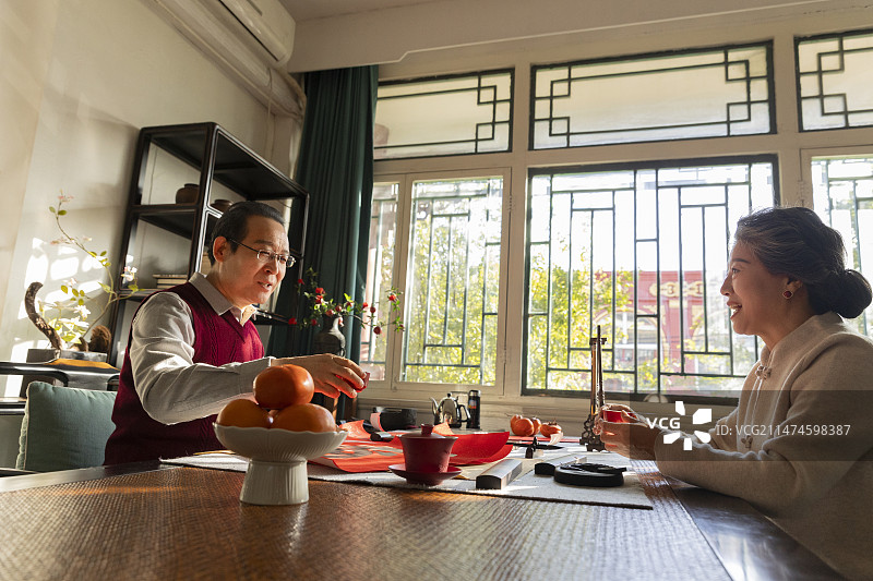东方家庭过年：老年夫妇在书房喝茶聊天、写春联和福字图片素材