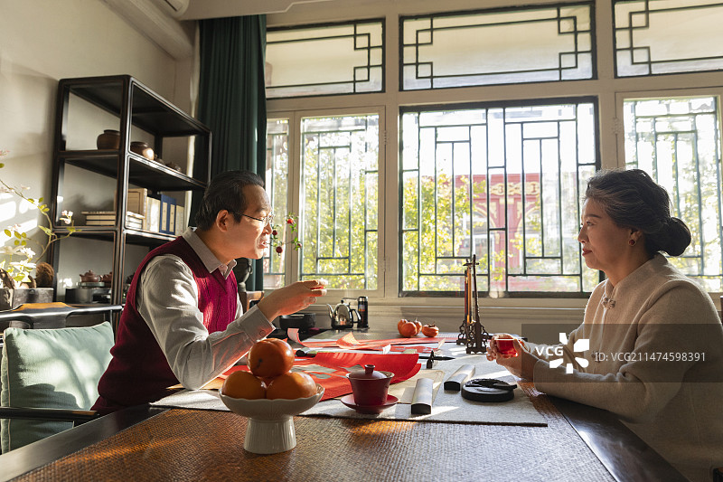 东方家庭过年：老年夫妇在书房喝茶聊天、写春联和福字图片素材