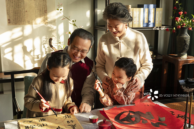 东方家庭过年：老年夫妇在书房教孙女和孙子写毛笔字图片素材