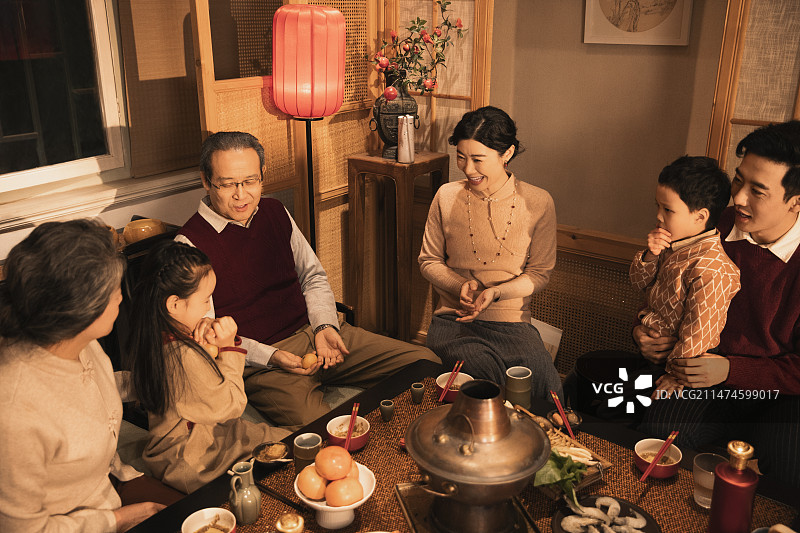 东方家庭过年：幸福一家人在客厅吃年夜饭、玩扔橘子游戏图片素材