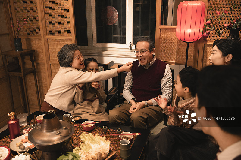 东方家庭过年：幸福一家人在客厅吃年夜饭、玩扔橘子游戏图片素材