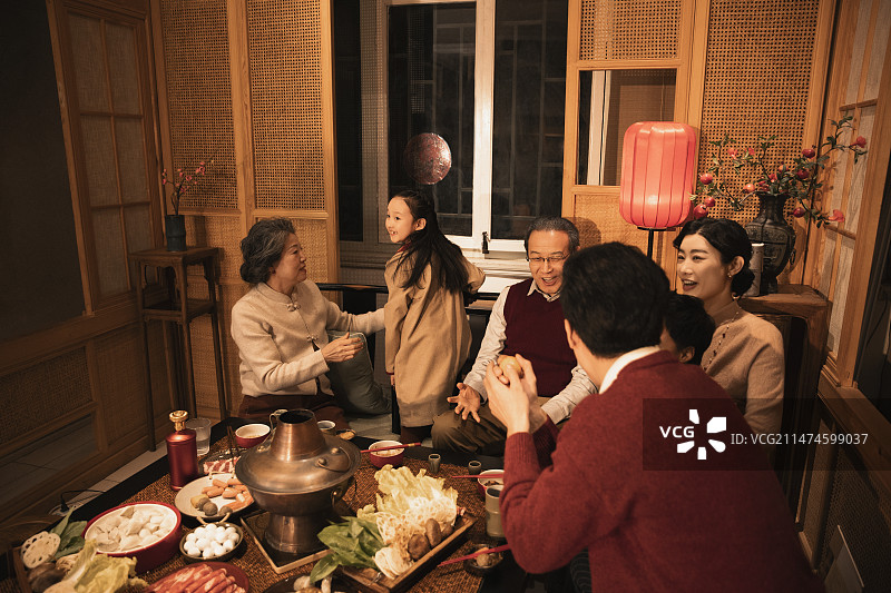 东方家庭过年：幸福一家人在客厅吃年夜饭、玩扔橘子游戏图片素材