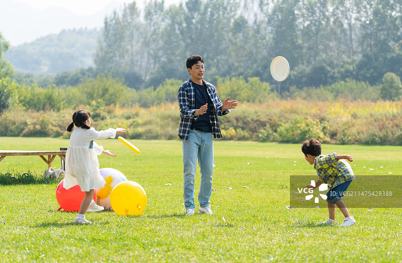 爸爸和孩子在草地上扔飞盘图片素材