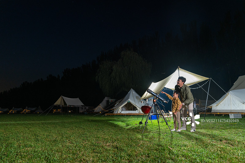 傍晚爸爸和儿子在露营地用望远镜看星空图片素材