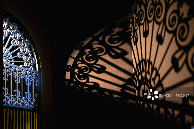 光线穿透大门铁栅栏的墙上投影图片素材