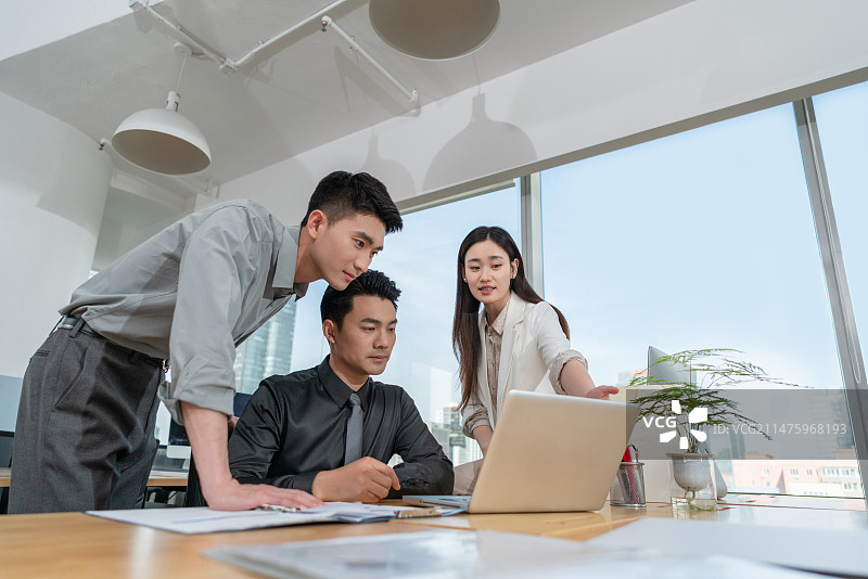 同事在办公桌前看电脑积极交流沟通工作图片素材