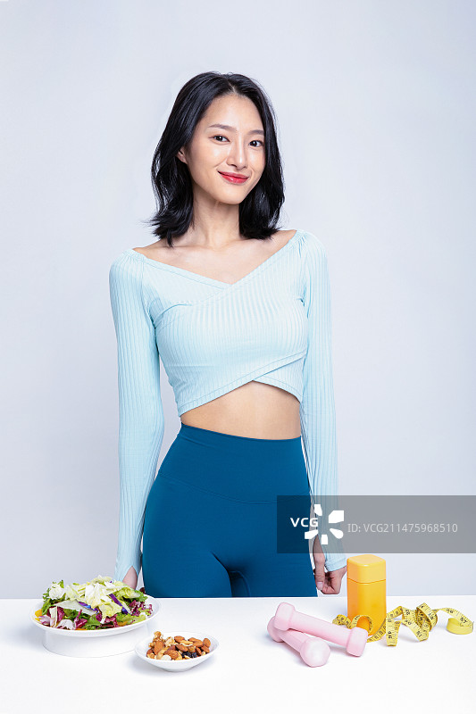 身穿运动服站在沙拉坚果舌下胶带卷尺药盒前的女人图片素材