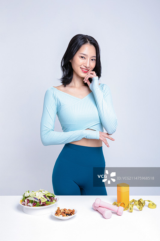 身穿运动服站在沙拉坚果舌下胶带卷尺药盒前的女人图片素材