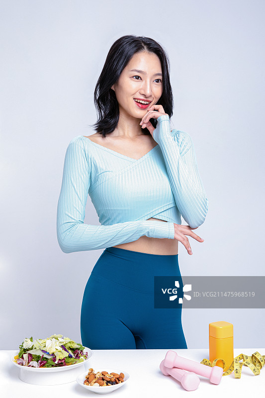 身穿运动服站在沙拉坚果舌下胶带卷尺药盒前的女人图片素材