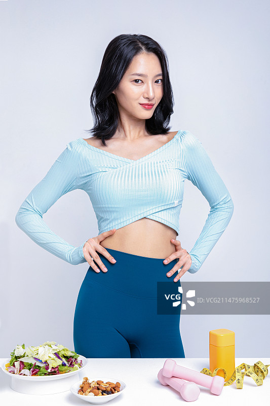 身穿运动服站在沙拉坚果舌下胶带卷尺药盒前的女人图片素材