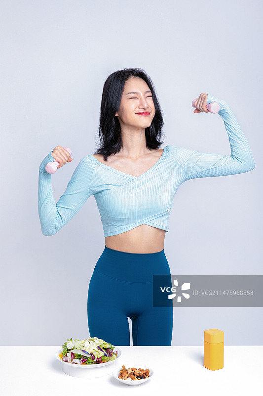 女人在沙拉坚果药盒前手拿哑铃图片素材