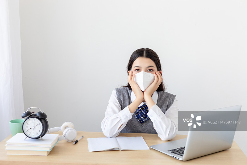 室内一个戴着KN95口罩的中国女大学生在学习图片素材