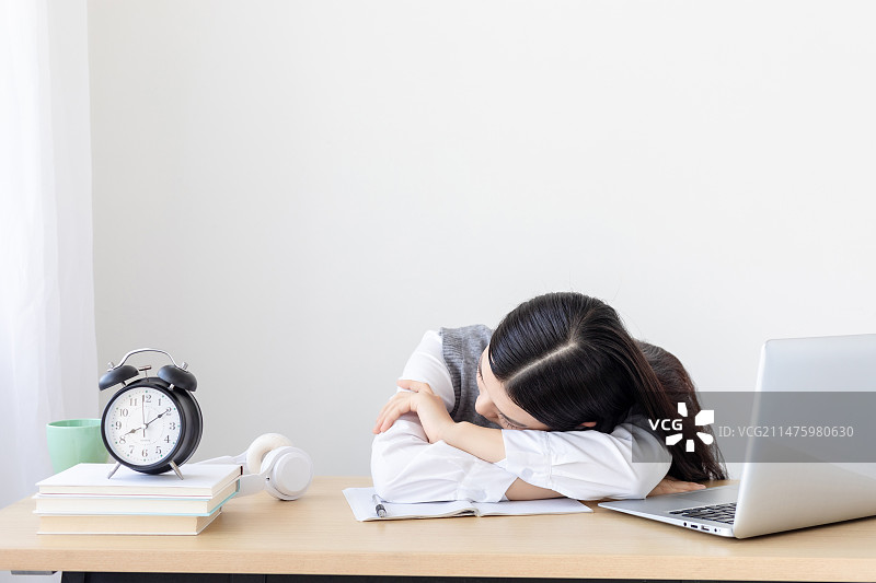 一个疲惫的中国女大学生趴在桌子上图片素材
