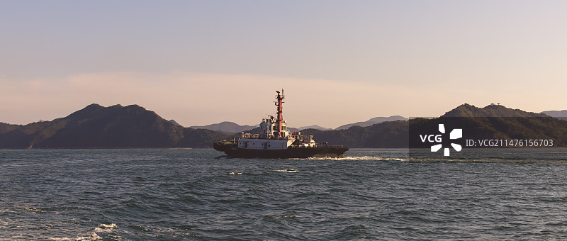 黄昏下深圳盐田港海域上航行的拖船图片素材