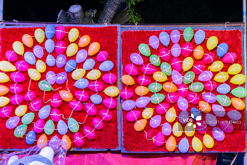 中国城市夜晚夜市拍摄主题，气枪打气球和排列整齐的彩色气球，户外无人图像摄影图片素材