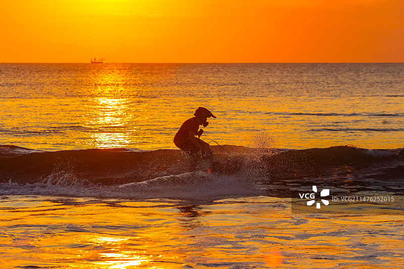 日落下海边冲浪的人图片素材