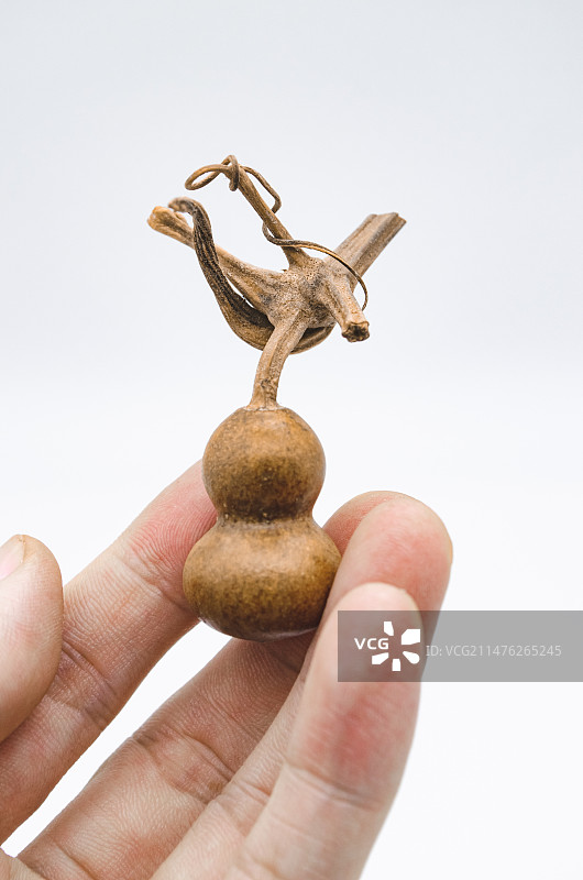 中国文玩拍摄主题，一个花皮脏皮的手捻盘玩的文玩八宝葫芦和龙头龙须，室内无人影棚拍摄图像摄影图片素材