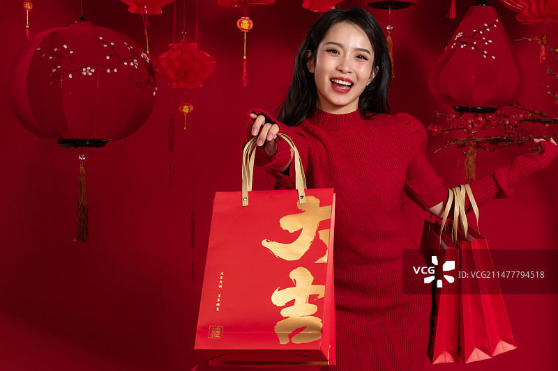 新年购物，红色背景下的一位亚洲青年女性拿着购物袋图片素材
