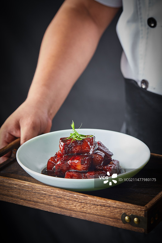 厨师端着一盘红烧肉图片素材